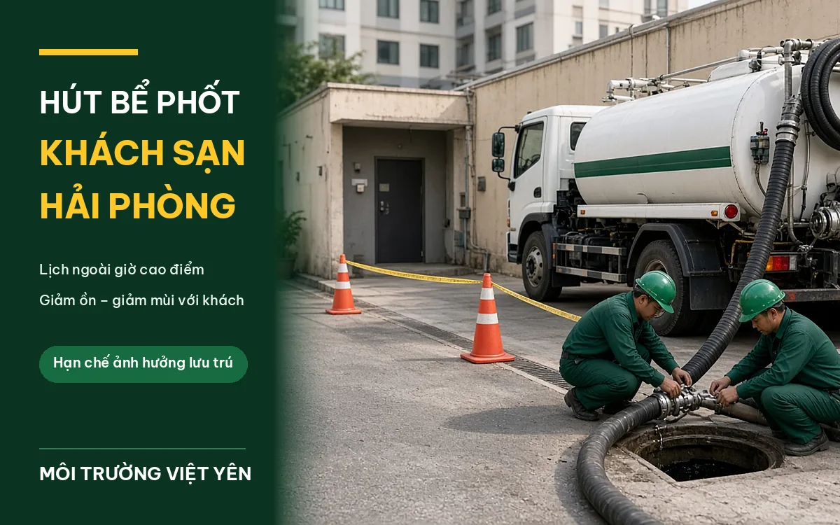 Xe hút bể phốt trắng sọc xanh của Môi Trường Việt Yên đỗ lối dịch vụ khách sạn Hải Phòng, hai kỹ thuật viên đồng phục xanh đậm mũ xanh thao tác tại miệng hầm, cọc tiêu cam và dây cảnh báo, ảnh bìa hút bể phốt khách sạn Hải Phòng